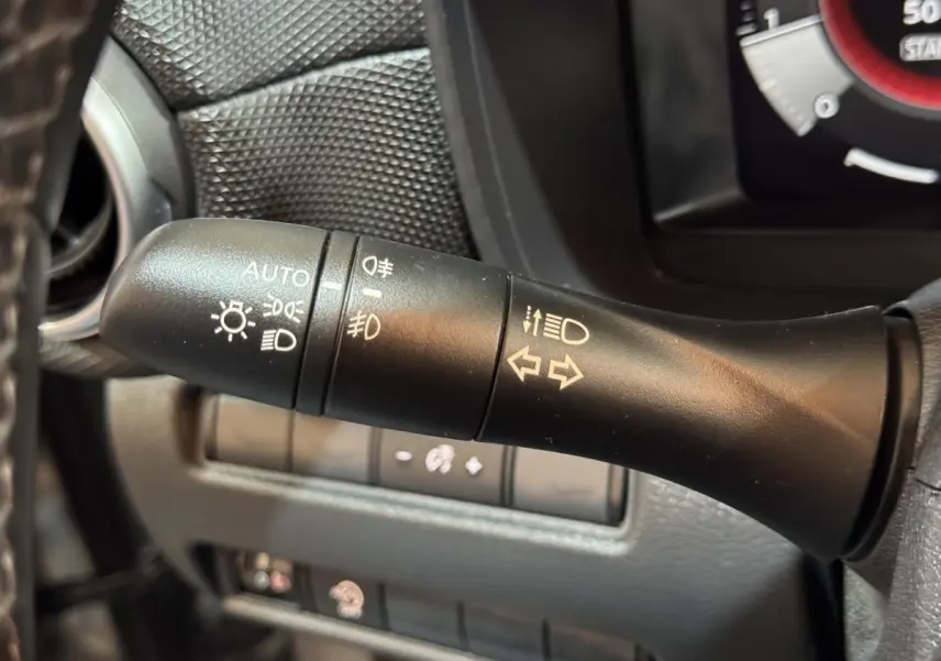 Gros plan sur la commande des feux et clignotants côté gauche du volant dans un Nissan Juke gris clair 2025.