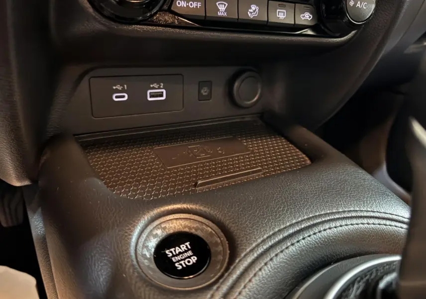 Gros plan intérieur sur la console centrale noire du Nissan Juke gris clair, montrant le bouton démarrage et ports USB.