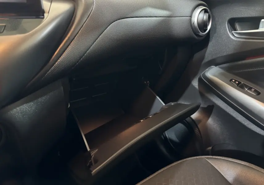 Vue intérieure côté passager du Nissan Juke 2025 gris clair, avec boîte à gants ouverte et détails de la porte.