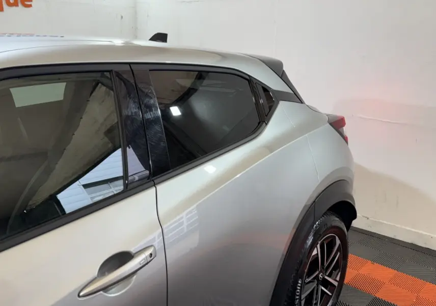 Vue latérale côté gauche du Nissan Juke gris clair 2025, mettant en valeur la ligne arrière et les jantes noires.