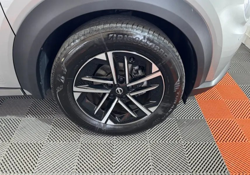 Gros plan sur la roue avant droite gris clair du Nissan Juke 2025 avec jante alliage noir et argentée.
