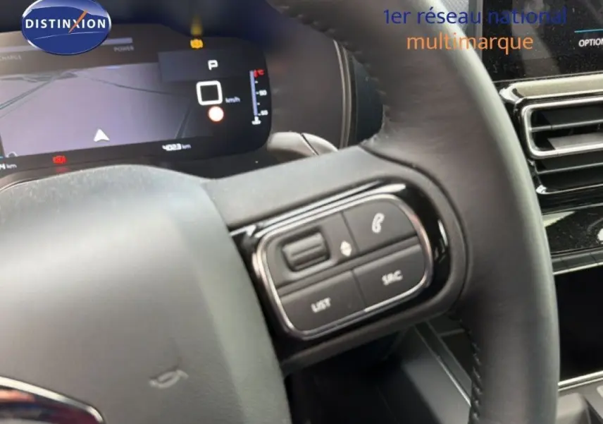 Gros plan sur le volant et le tableau de bord numérique du Citroën C5 Aircross Hybrid gris platinium, avec commandes au volant visibles.