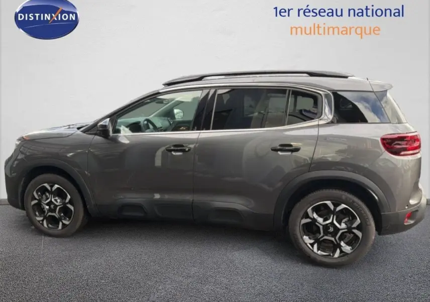 Vue de profil côté gauche du Citroën C5 Aircross Hybrid gris platinium avec jantes bi-ton et barres de toit.