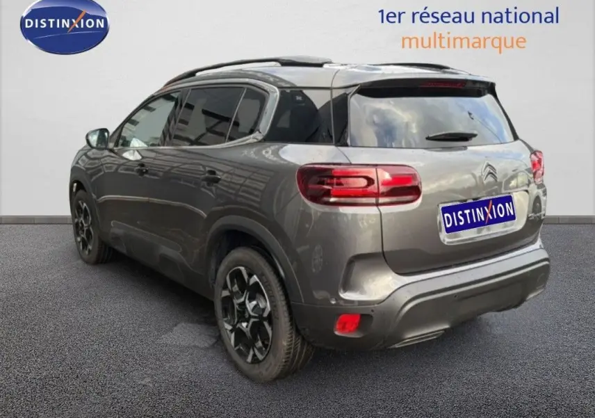 Vue 3/4 arrière droite d’un Citroën C5 Aircross Hybrid gris platinium avec jantes noires bicolores et vitres teintées.