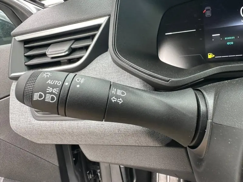 Gros plan sur la commande des feux et clignotants dans l’habitacle gris d’une Renault Clio 2025 côté gauche du volant.