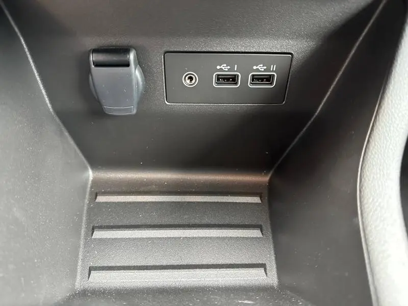 Vue rapprochée de la console centrale d'une Renault Clio 2025 grise, montrant deux ports USB et une prise auxiliaire.