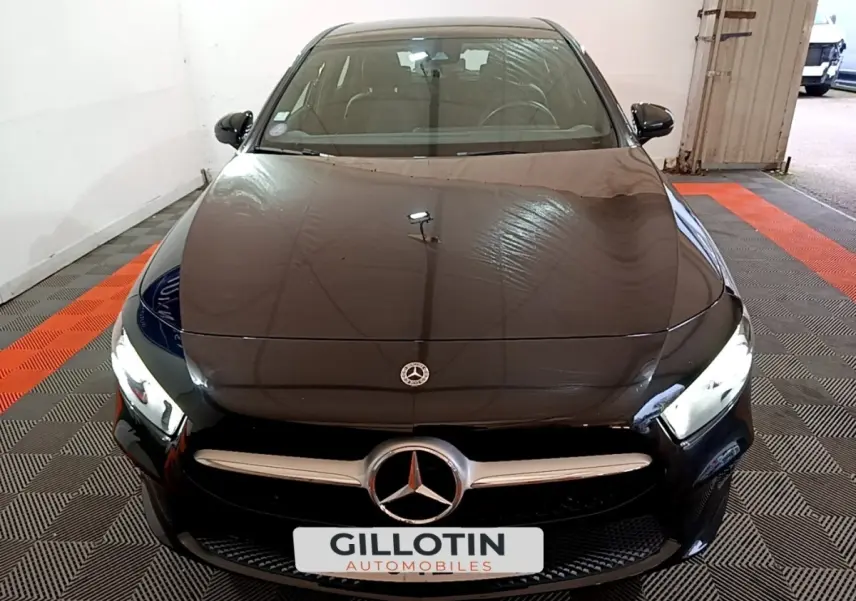 Vue avant d'une Mercedes Classe A 250 e Business Line noire avec phares LED allumés en intérieur.