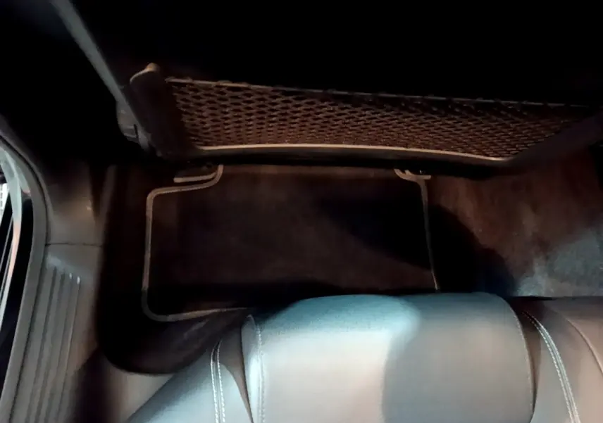 Détail du coffre arrière avec filet de rangement et tapis noir dans une Mercedes Classe A A 250 e Business Line 2020.
