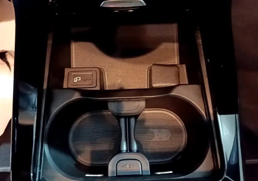 Gros plan sur la console centrale noire de la Mercedes Classe A 250 e Business Line 2020, avec porte-gobelets et chargeur sans fil.