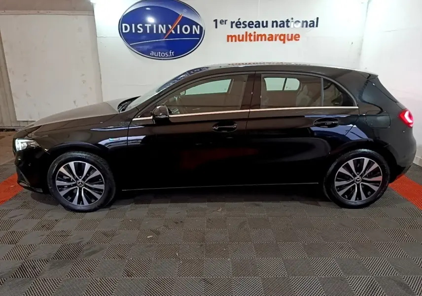 Vue de profil côté gauche d'une Mercedes Classe A 250 e Business Line noire avec feux arrière allumés en intérieur showroom.