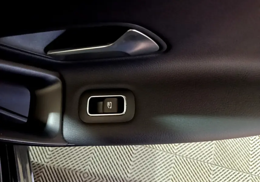 Gros plan sur la poignée intérieure et le bouton de verrouillage de la porte côté gauche d’une Mercedes Classe A noire.
