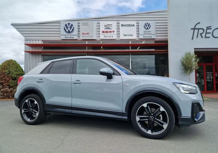 Audi Q2 35 TFSI 2023 gris flèche vue de profil côté gauche avec jantes sport 18'' et finition S line.