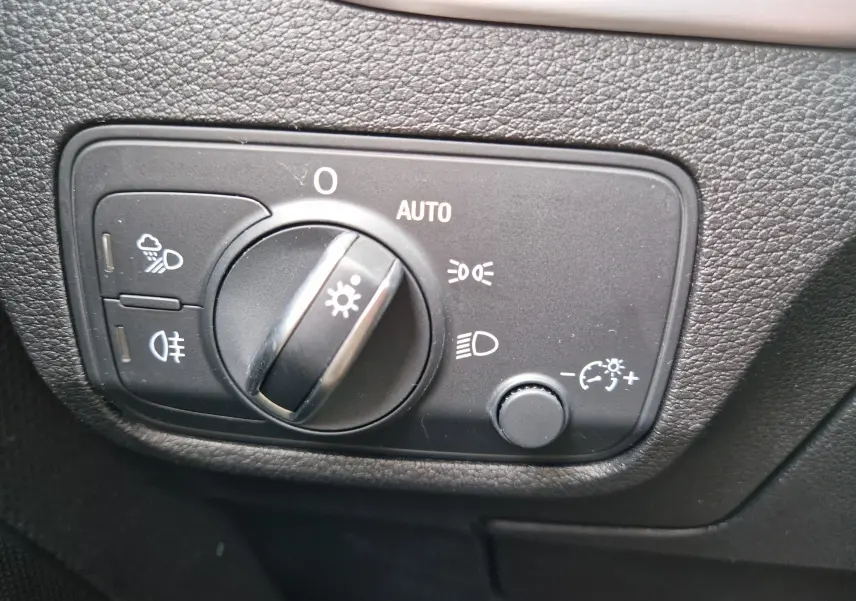 Gros plan sur le bouton de commande des phares dans l’habitacle de l’Audi Q2 35 TFSI gris flèche, finition S line.