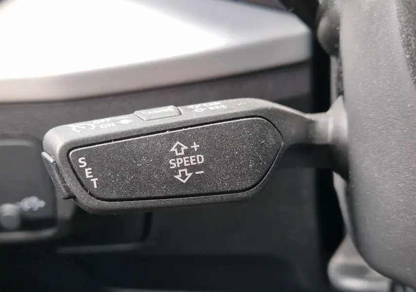 Gros plan sur la commande de régulateur de vitesse du volant d’un Audi Q2 35 TFSI gris flèche, finition S line.