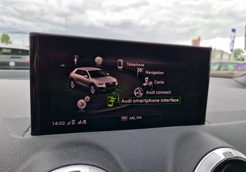 Écran central de l’Audi Q2 2023 affichant l’interface MMI avec navigation et smartphone, vue intérieure frontale.