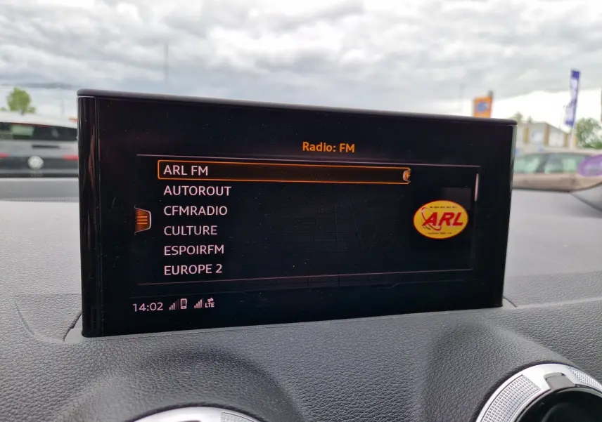 Écran central MMI navigation affichant les stations FM dans l’Audi Q2 35 TFSI gris flèche, vue intérieure avant.