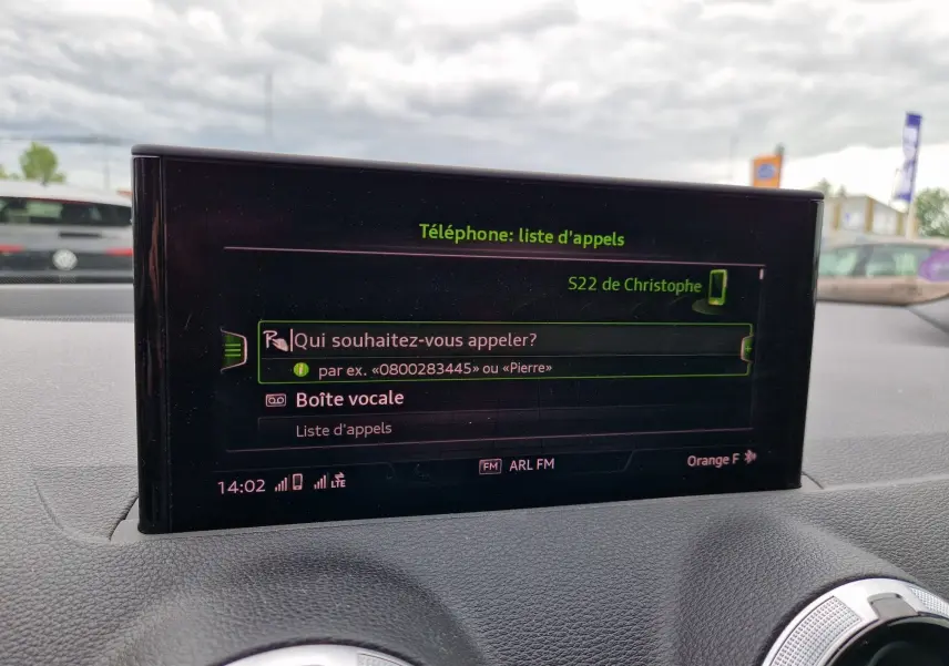 Écran central MMI tactile de l'Audi Q2 35 TFSI 2023 affichant la liste d'appels, intérieur gris et aluminium brossé.