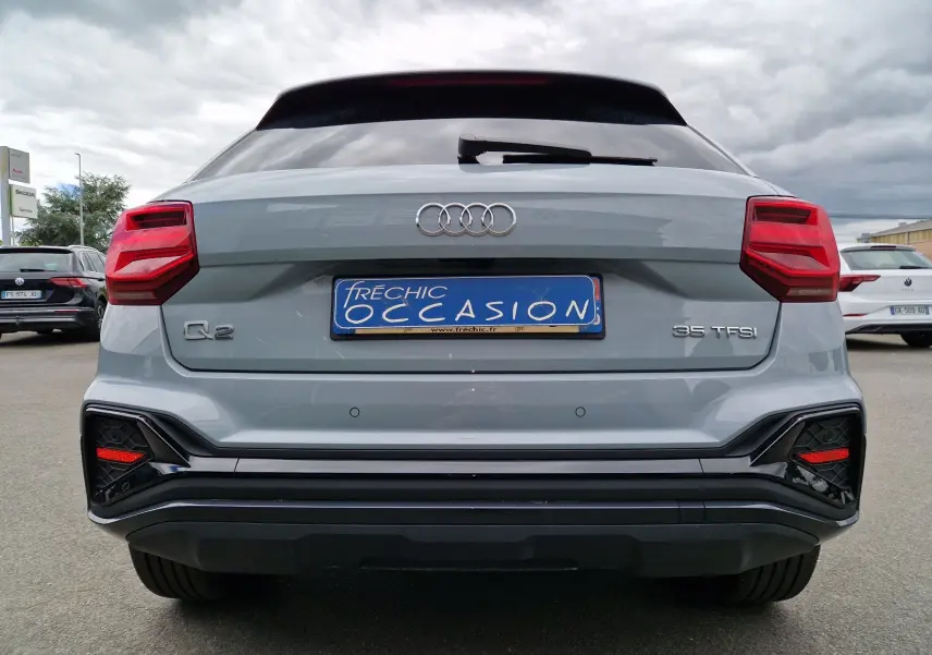 Vue arrière de l'Audi Q2 35 TFSI 2023 en gris flèche, avec feux rouges et détails noirs contrastants.