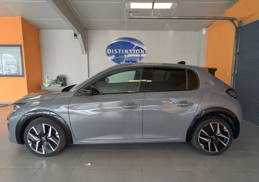 Profil droit de la Peugeot 208 HYBRID 145 GT gris selenium avec jantes alliage 17 pouces et vitres arrière surteintées.