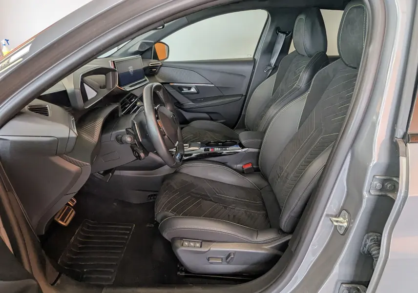 Vue intérieure côté conducteur de la Peugeot 208 Hybrid 145 gris selenium, sièges Alcantara noir avec surpiqûres vertes.