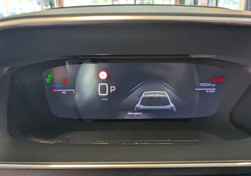 Affichage numérique du tableau de bord du Peugeot 208 Hybrid 145, montrant la voiture vue de dessus et les indicateurs de vitesse et énergie.