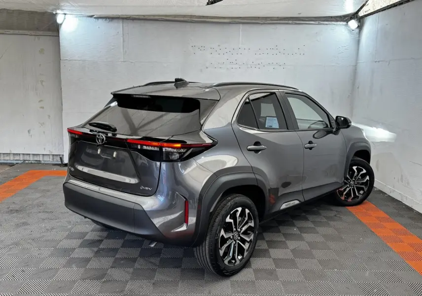 Toyota Yaris Cross gris foncé vue 3/4 arrière droit, avec feux arrière LED et jantes alliage noires.