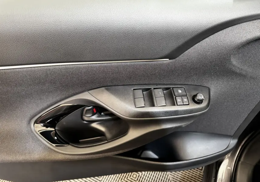 Vue rapprochée de la porte avant gauche grise du Toyota Yaris Cross 2026, avec commandes électriques et poignée noire.