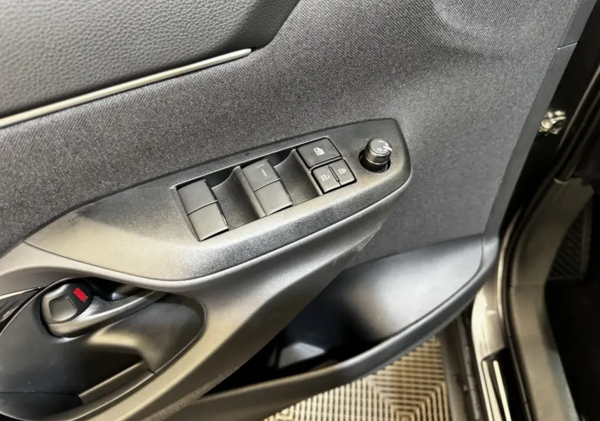 Gros plan sur la porte côté conducteur de la Toyota Yaris Cross gris foncé, avec commandes des vitres et rétroviseurs.