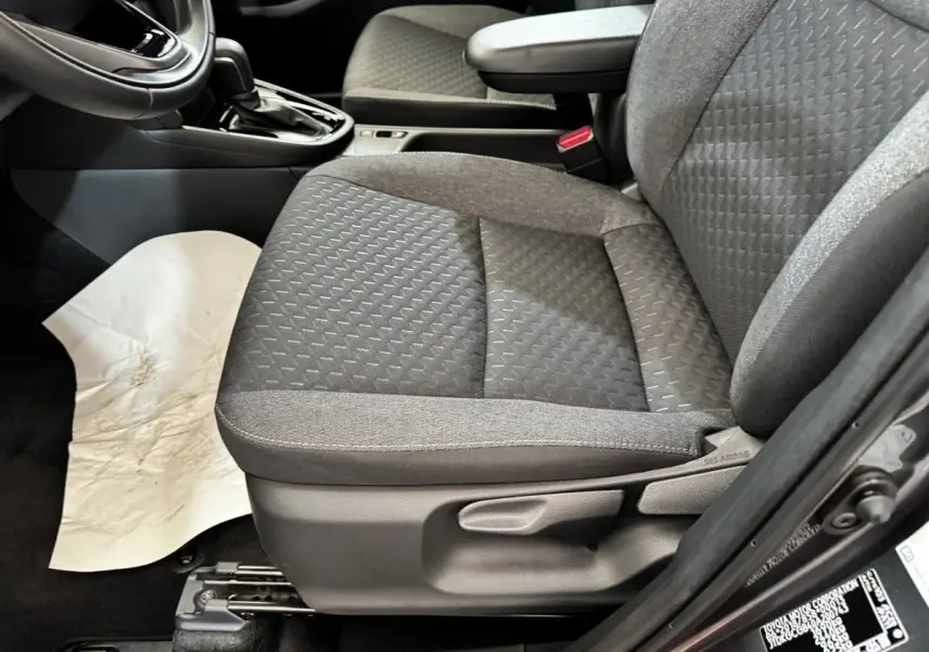 Gros plan sur le siège avant droit gris foncé de la Toyota Yaris Cross 2026, avec accoudoir et levier de boîte automatique visible.