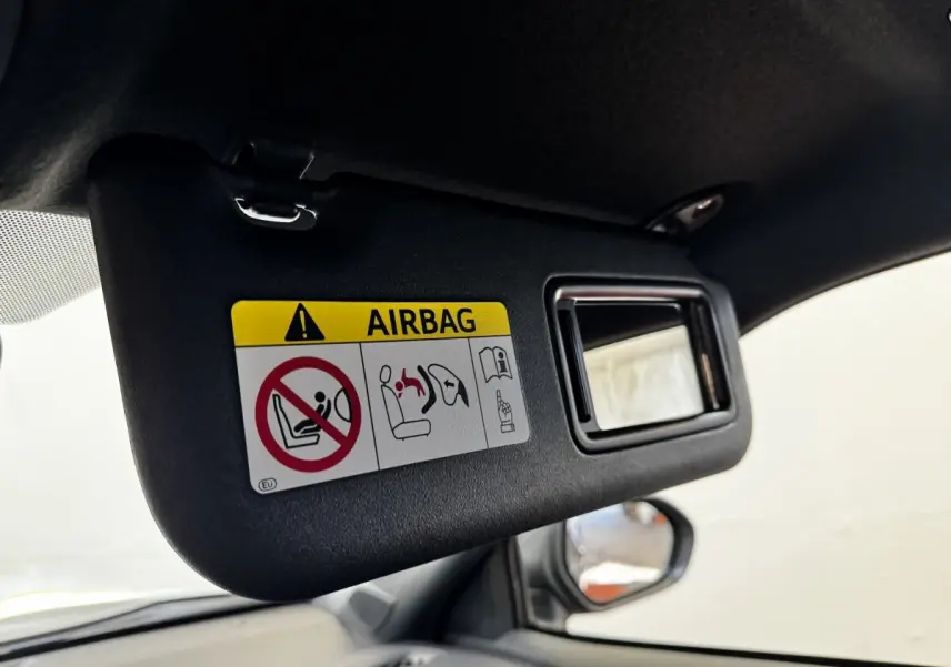 Détail du pare-soleil côté conducteur avec miroir et avertissement airbag dans un Toyota Yaris Cross gris foncé.