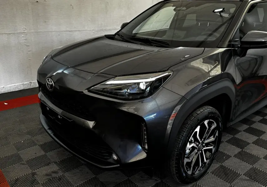 Toyota Yaris Cross gris foncé vue 3/4 avant droit, avec phares LED et jantes alliage distinctives.