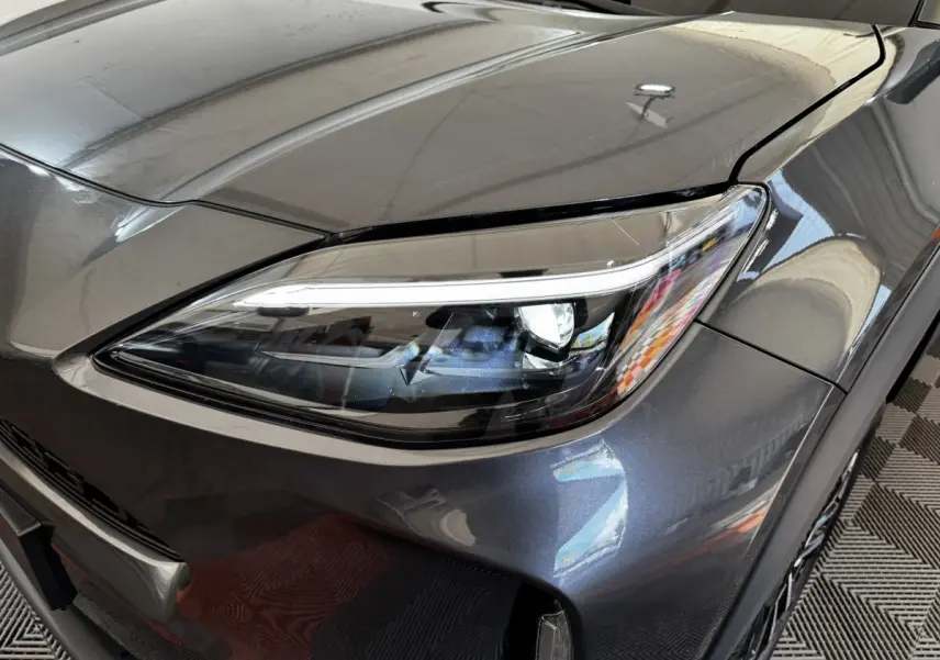 Gros plan sur le phare avant droit du Toyota Yaris Cross gris foncé 2026, soulignant ses lignes modernes et LED.