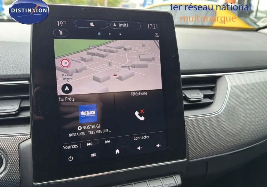 Vue rapprochée de l'écran tactile central du tableau de bord du Renault Arkana gris avec navigation et radio affichées.