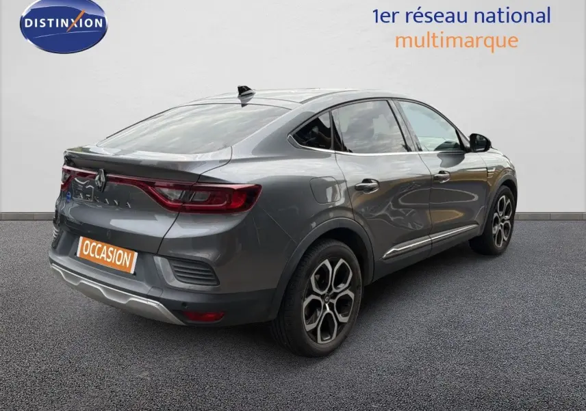 Renault Arkana gris en 3/4 arrière droit, avec feux LED et jantes bi-ton distinctives sur sol gris.