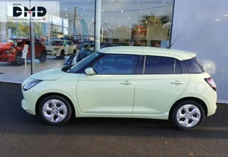 Vue latérale droite d'une Suzuki Swift 1.2 Privilège Hybrid 2024 en Cool Yellow avec toit blanc, garée devant un showroom.