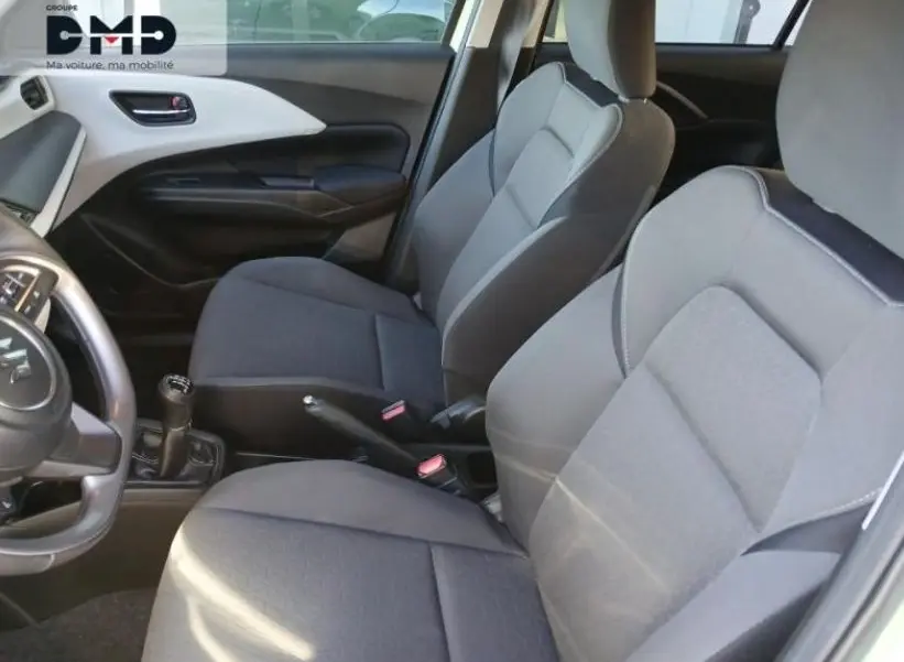 Vue intérieure côté gauche de la Suzuki Swift 1.2 Privilège Hybrid 2024, sièges tissu gris et volant cuir noir.