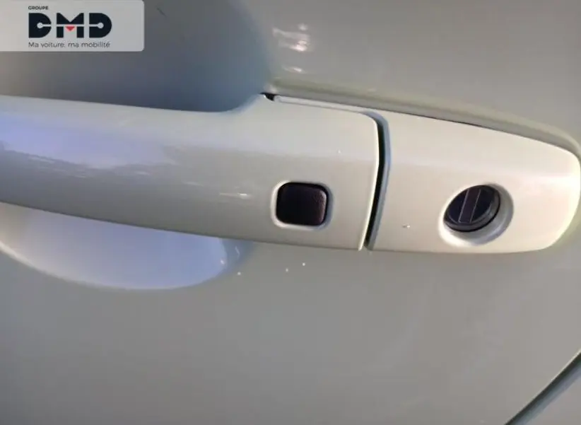 Gros plan sur la poignée de porte avant droite blanche d'une Suzuki Swift 1.2 Privilège Hybrid 2024.