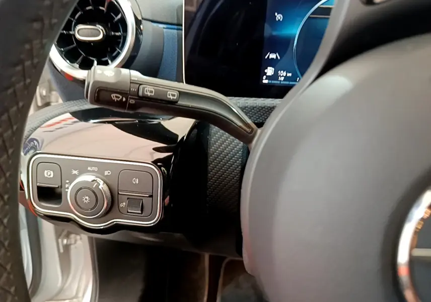 Gros plan sur la commande des phares et le commodo d’essuie-glace côté gauche du tableau de bord gris clair de la Mercedes Classe A 180 d.