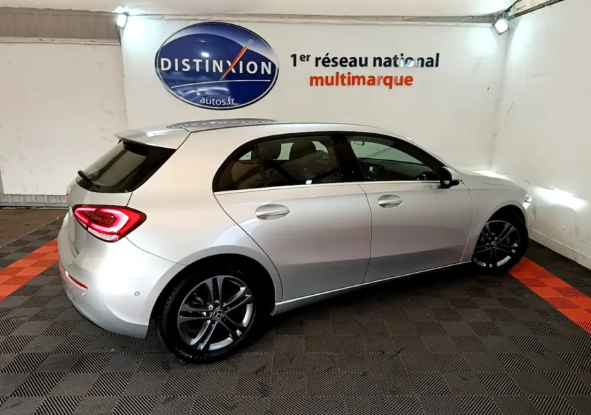 Vue 3/4 arrière droite d'une Mercedes Classe A A 180 d Business Line gris clair dans un showroom intérieur.