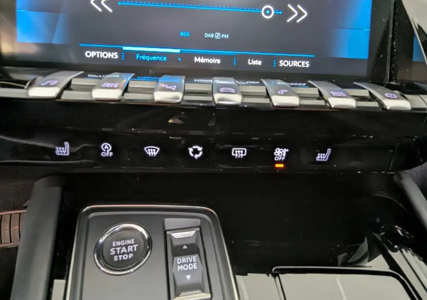 Détail de la console centrale de la Peugeot 508 SW gris 2021, avec boutons de commande et écran tactile en arrière-plan.