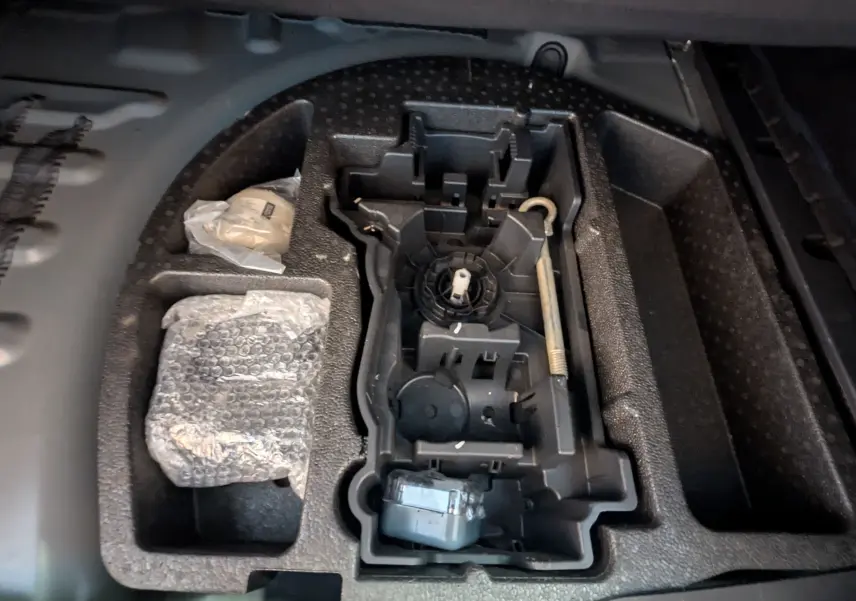 Rangement sous le coffre de la Peugeot 508 SW gris 2021, vue plongeante sur l’emplacement des outils et accessoires.