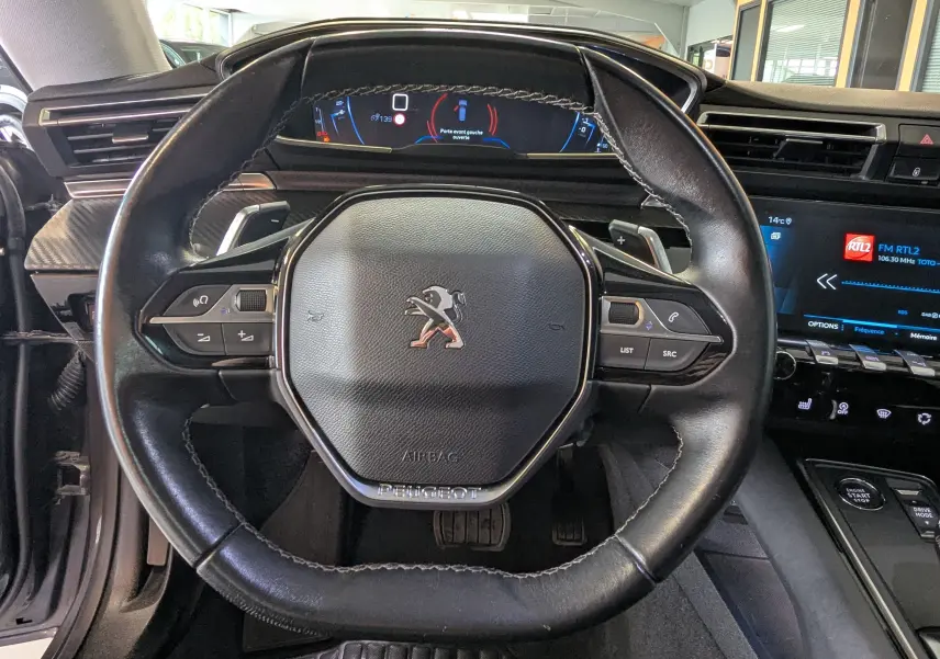 Vue rapprochée du volant cuir noir du Peugeot 508 SW 2021 avec tableau de bord numérique et écran tactile central.