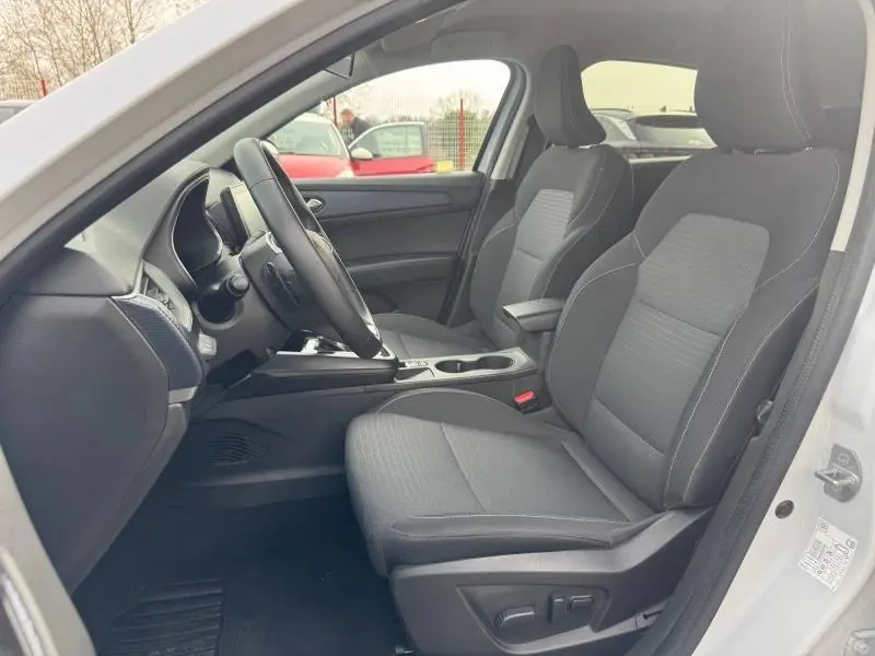 Vue intérieure côté conducteur du Renault Arkana blanc 2025, montrant les sièges avant et le tableau de bord moderne.