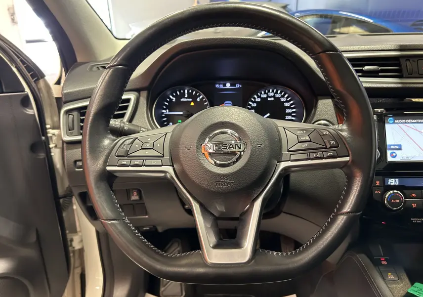 Vue rapprochée du volant cuir noir du Nissan Qashqai blanc 2018 avec tableau de bord et écran tactile visible.