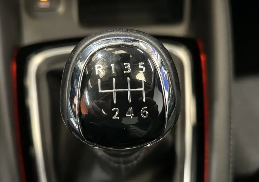 Gros plan sur le levier de vitesses manuel noir et chrome du Nissan Qashqai blanc, montrant les six rapports et la marche arrière.