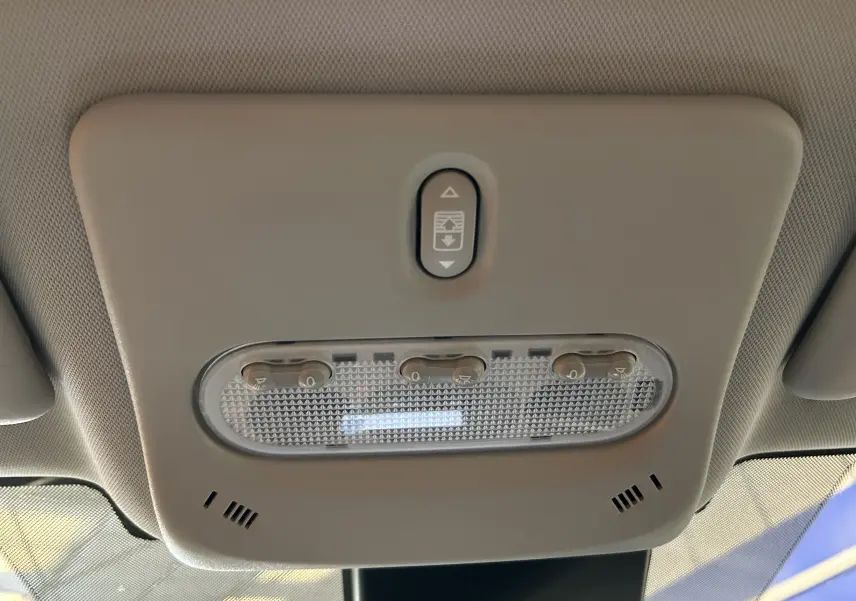 Plafonnier intérieur beige avec commandes d’éclairage et ouverture du toit panoramique sur Nissan Qashqai blanc, vue de dessous.