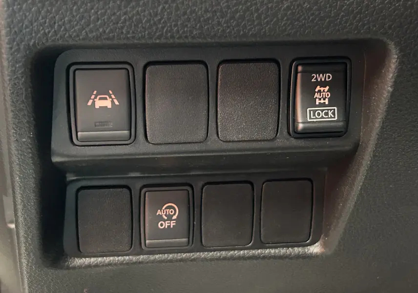 Gros plan sur les boutons de commande du tableau de bord du Nissan Qashqai blanc, avec fonction 4x4 et assistance à la conduite.