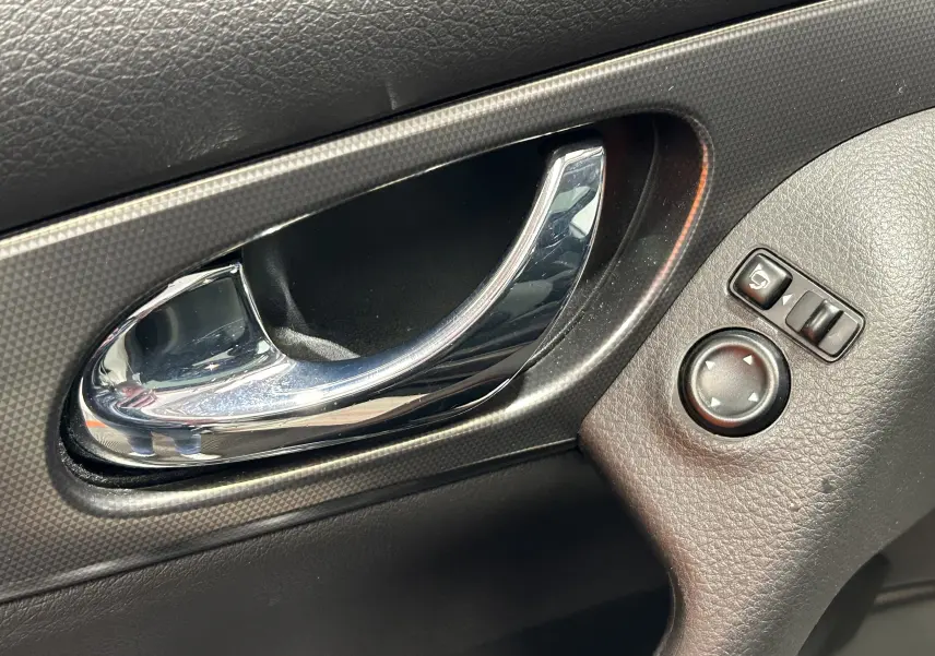 Poignée de porte intérieure chromée côté conducteur du Nissan Qashqai 2018 avec commandes de réglage des rétroviseurs.