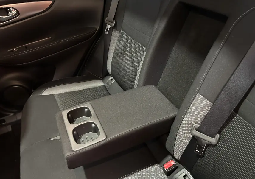 Vue rapprochée de la banquette arrière du Nissan Qashqai 2018 avec accoudoir central et porte-gobelets intégrés.