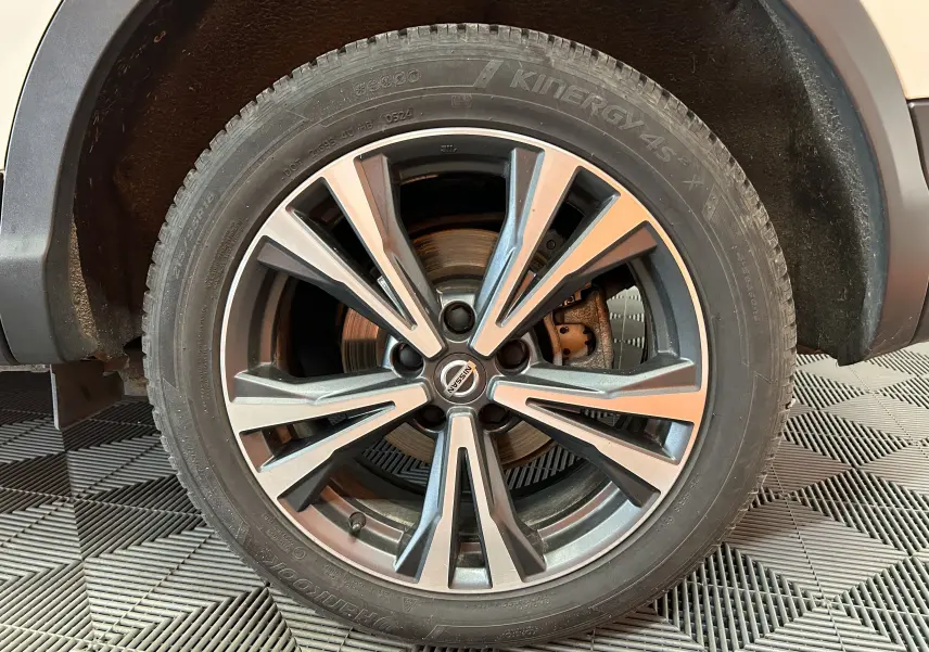 Gros plan sur la roue avant gauche du Nissan Qashqai blanc avec jante alliage bicolore et pneu Hankook.